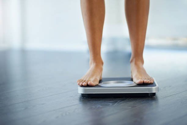 Shot of an unrecognizable woman weighing herself at home Shot of an unrecognizable woman weighing herself at home
